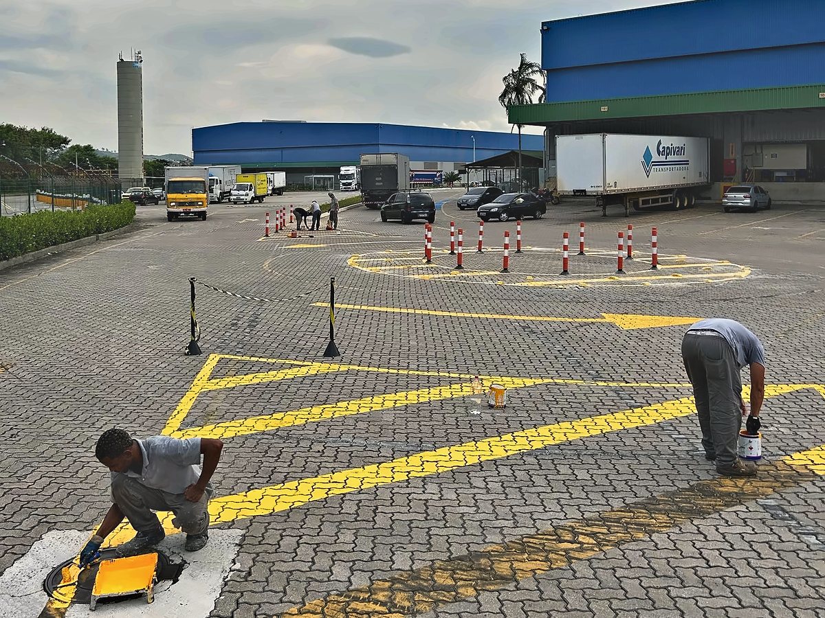Equipe pintando a demarcação viária em amarelo no pátio de um condomínio logístico